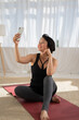 © Sibstock/Stocksy - woman using phone after yoga class, selfie