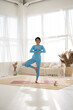 © Sibstock/Stocksy - asian girl practices yoga at home. Summer tropical interior