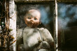 © Helen Rushbrook/Stocksy - Slightly creepy baby doll at a window