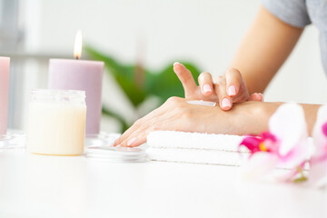 Woman applying hand cream at home, closeup