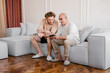 © Alina Hvostikova/Stocksy - Young man teaching senior father to play video game