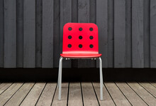 Red Empty Chair Against Black Wooden Wall