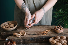 Tattooed Woman Cracking Nuts On Wooden Cutting Board