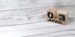 © 07LEO - Vintage wooden calendar block real date 03 and the month of April on a light wooden table, copy the text space next to the April symbol