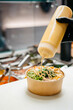 © Sergio Marcos/Stocksy - Anonymous waiter putting sauce on a poke bowl