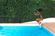 © David Prado/Stocksy - Happy woman jumping into pool