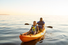 Smiling Boy In Tandem Orange Kayak With Father