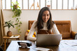 © Malquerida Studio/Stocksy - Smiling female freelancer working at office while listening to music with earphones