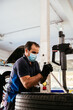 © David Prado/Stocksy - Male technician checking wheel near colleagues