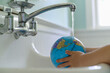 © jamie grill photography/Stocksy - Child Washing Globe in Sink