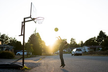 Boy Jumps To Shoot Basketball In Cul Du Sac