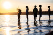 © Jennifer Bogle/Stocksy - Silhouette of girl flipping hair in ocean with friends