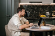 © Alina Hvostikova/Stocksy - Male freelancer using laptop in kitchen