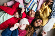 © BONNINSTUDIO/Stocksy - Funny diverse children in outerwear lying on floor