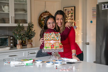 Happy Mother And Daughter With Gingerbread House They Built