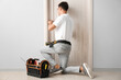 © Pixel-Shot - Construction worker repairing door indoors
