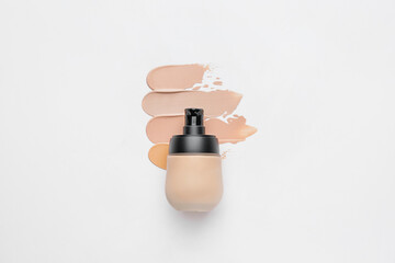 Bottle of makeup foundation and samples on white background