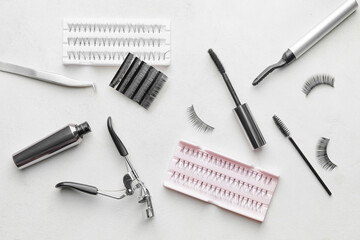 Composition with false eyelashes and tools on light background