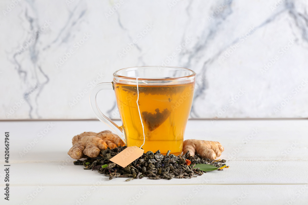 Cup of aromatic black tea on light background