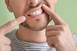 © Pixel-Shot - Man suffering from tooth ache on color background, closeup