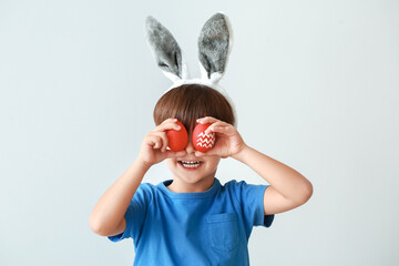 Poster - Cute little boy with bunny ears and Easter eggs on grey background