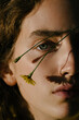 © Ivan Ozerov/Stocksy - Young woman with wildflower near face