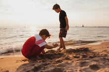 Two Brothers Playing In The Sand At Lake Michigan.