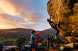 © Manu Prats/Stocksy - Man climbing granite boulder rock near friends