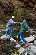 © Bisual Studio/Stocksy - Young man helping his girlfriend to cross the river