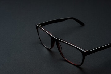 Stylish men's glasses in a black frame on black background.