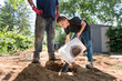 © Jennifer Bogle/Stocksy - Boy pours bucket of gravel.