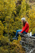 © Bisual Studio/Stocksy - Woman siiting on a rock at nature on autumn day