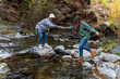 © Bisual Studio/Stocksy - Young man helping his girlfriend to cross the river
