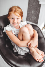 Portrait Of A Beautiful Redhead Girl Snuggling Up In A Chair