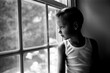 © Jakob Lagerstedt/Stocksy - A handsome young boy in a tank top looking out a window