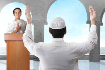 Wall Mural - Rear view of Asian Muslim man standing while raised hands and praying