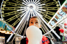 Trendy Woman Standing In Front Of Fair Wheel Holding A Cotton Candy