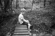 © Jakob Lagerstedt/Stocksy - Young boy sitting on a bridge in the woods