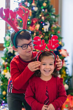 Playful Siblings In Front Of A Christmas Tree