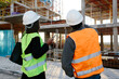 © Jimena Roquero/Stocksy - Back of Woman engineer and construction worker checking the development of a building in construcion.