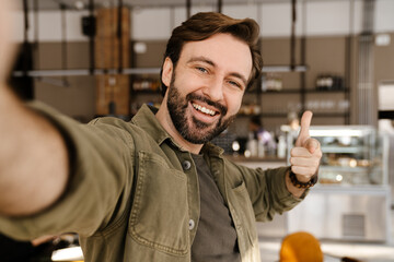 White man smiling and pointing finger at camera while taking selfie photo