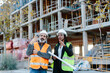 © Jimena Roquero/Stocksy - Woman engineer talking with construction worker in front of a building in construction