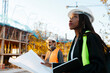 © Jimena Roquero/Stocksy - Woman engineer supervising the development of a building in construction checking the plans.