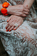 Closeup Of An Elder Woman With Orange Nail Polish, Bracelet And Flower Ring
