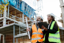 Woman Engineer Supervising Construction Of Building With Construction Worker Checking Her Tablet Device