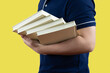 © Midnight Studio - Close up of man with a stack of books, lifestyle and education concept , university student use one hand holding heavy book stack for back to school concept portrait on yellow isolated background..