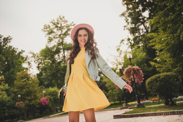 Poster - Photo of shiny charming woman dressed yellow dress pink headwear purse walking dancing smiling outside urban city street