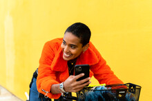 Young Trendy Woman With Bicycle Using Mobile Phone And Laughing