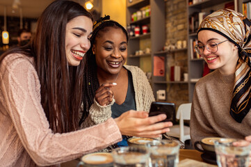 Three young multiethnic female friends spending time together at a coffee shop.