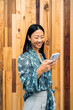 © Nunez Image/Stocksy - Asian Woman Using Phone in Office